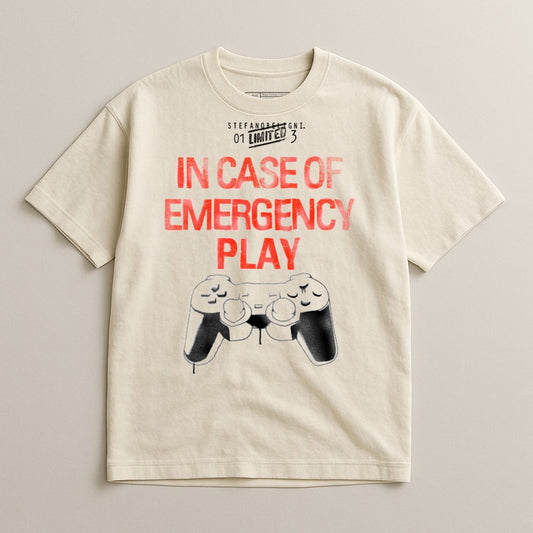 Cream t-shirt with "IN CASE OF EMERGENCY PLAY" and a black video game controller graphic.
