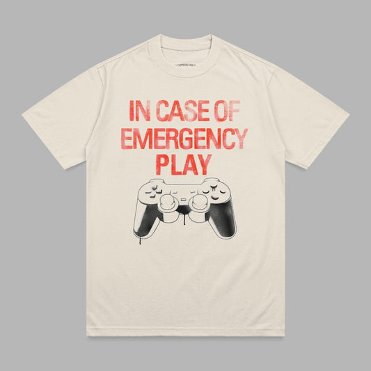 Cream t-shirt with red "IN CASE OF EMERGENCY PLAY" text and a video game controller.