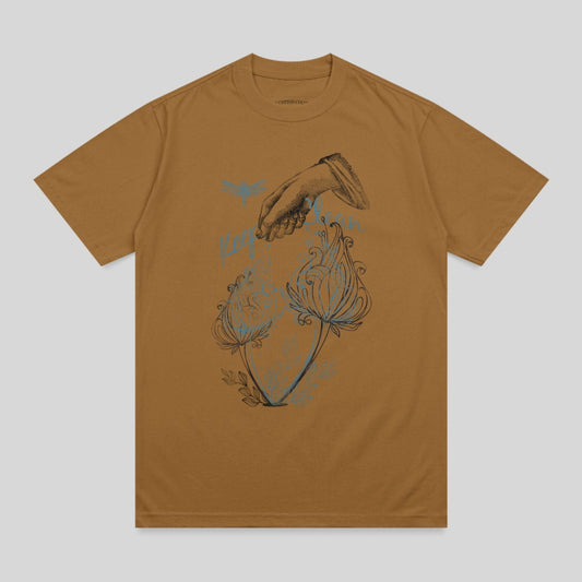 Brown t-shirt with a line drawing of a hand pouring water over two flowers.