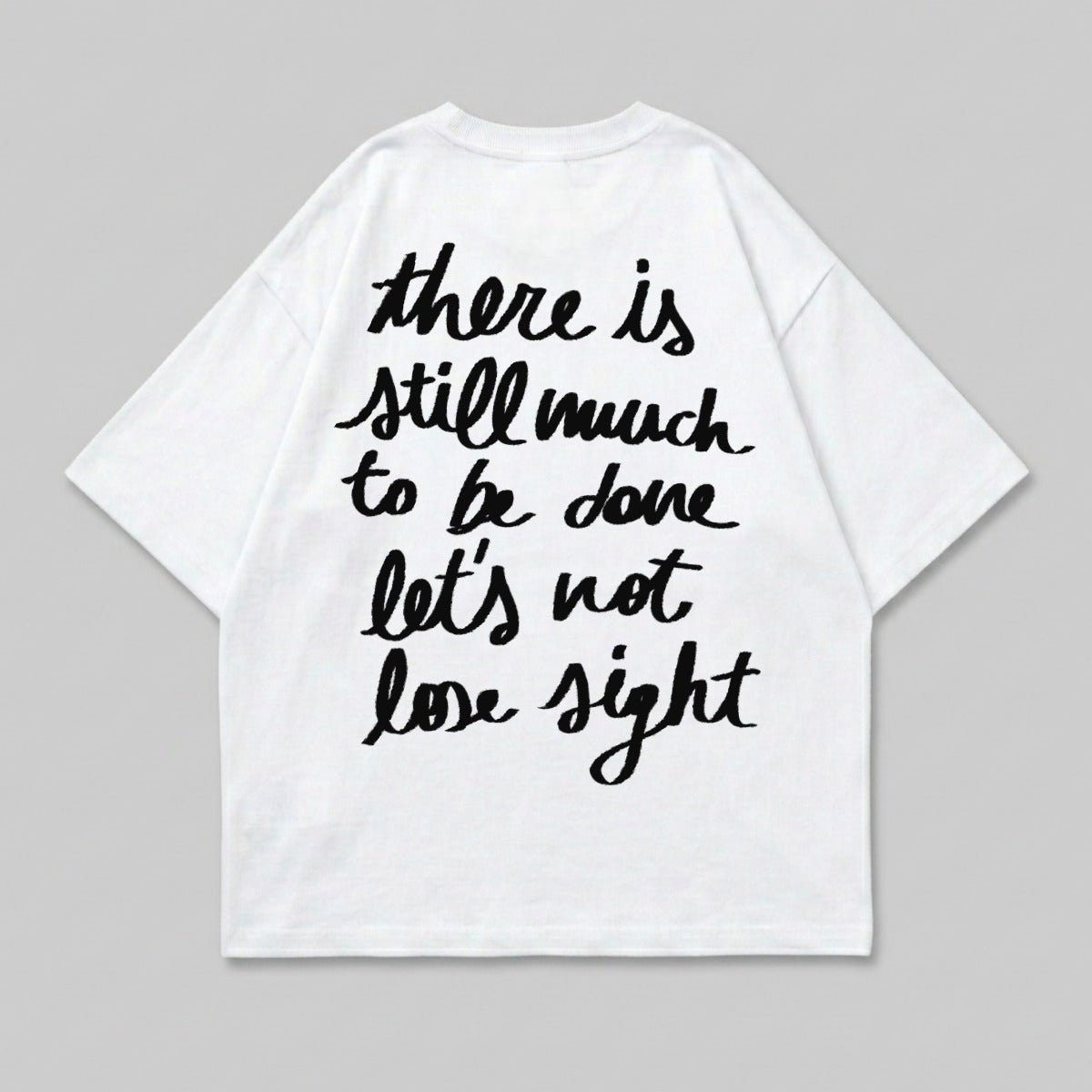 White t-shirt with black handwritten text "there is still much to be done let's not lose sight".