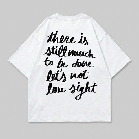 White t-shirt with black handwritten text "there is still much to be done let's not lose sight".