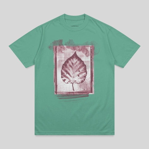 Teal t-shirt with a dark red leaf print inside a watercolor-style frame.