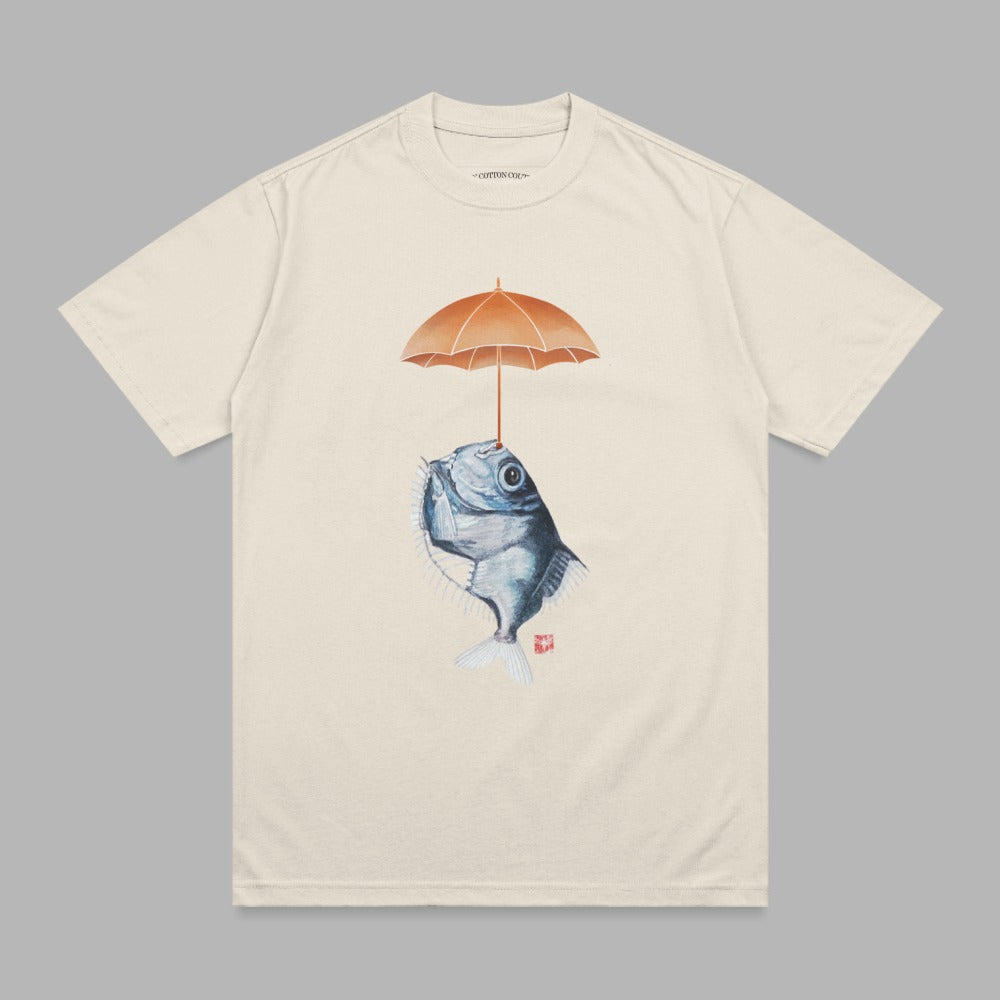 Cream t-shirt with a stylized fish holding an orange umbrella above its head.