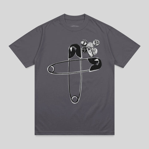 Dark grey t-shirt with two large safety pins and several small pins with graphic designs.