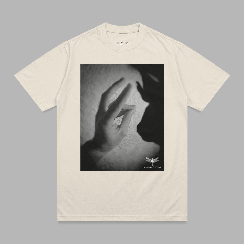 Cream t-shirt with a black and white graphic of hands and shadow.