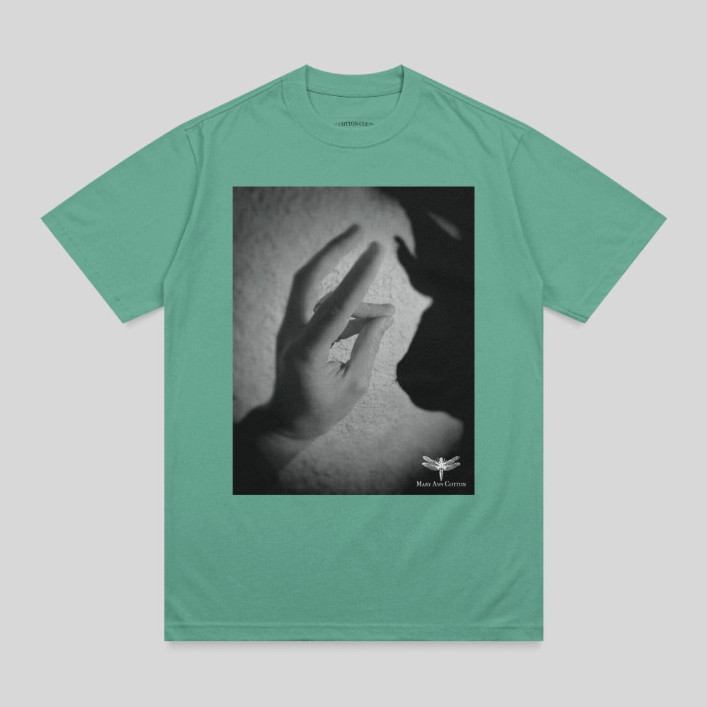 Green t-shirt with a black and white graphic of a hand reaching towards a shadow.