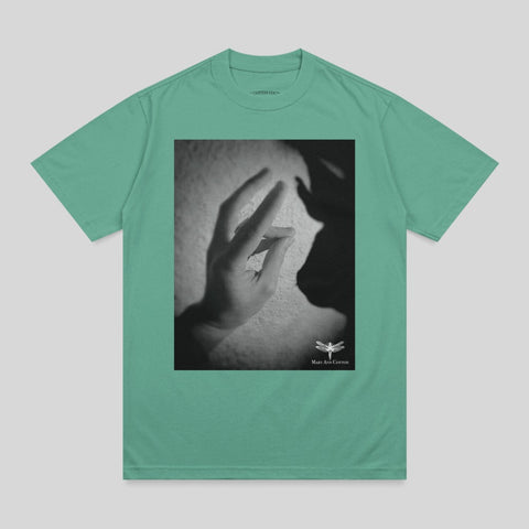 Green t-shirt with a black and white graphic of a hand reaching towards a shadow.