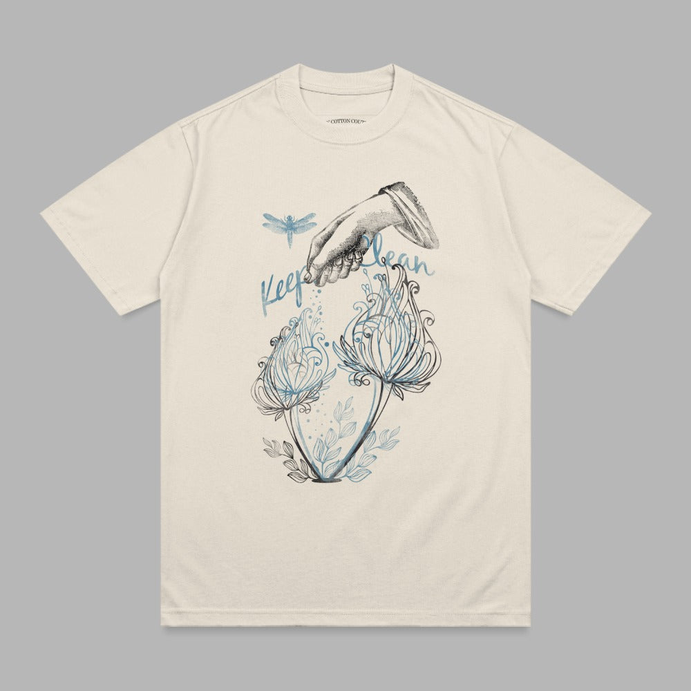 Cream t-shirt with a "Keep Clean" graphic featuring a hand pouring water on flowers and a dragonfly.
