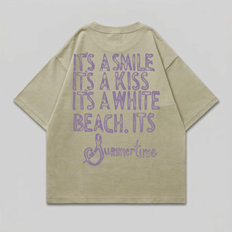 Light tan t-shirt with purple text: "It's a smile, it's a kiss, it's a white beach. Summertime".