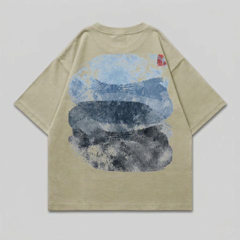 Tan t-shirt with abstract blue and grey brushstroke design on the back.