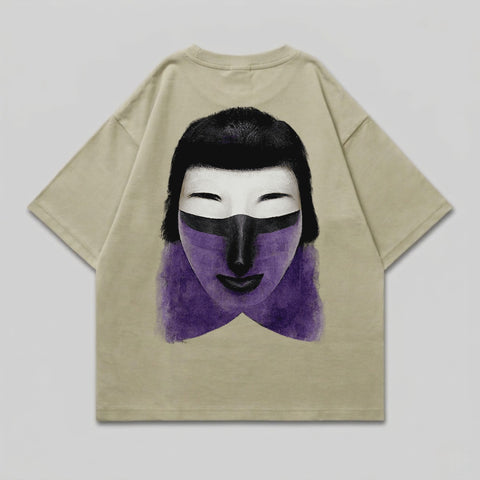 Light tan t-shirt with a graphic of a stylized face with purple and black markings.