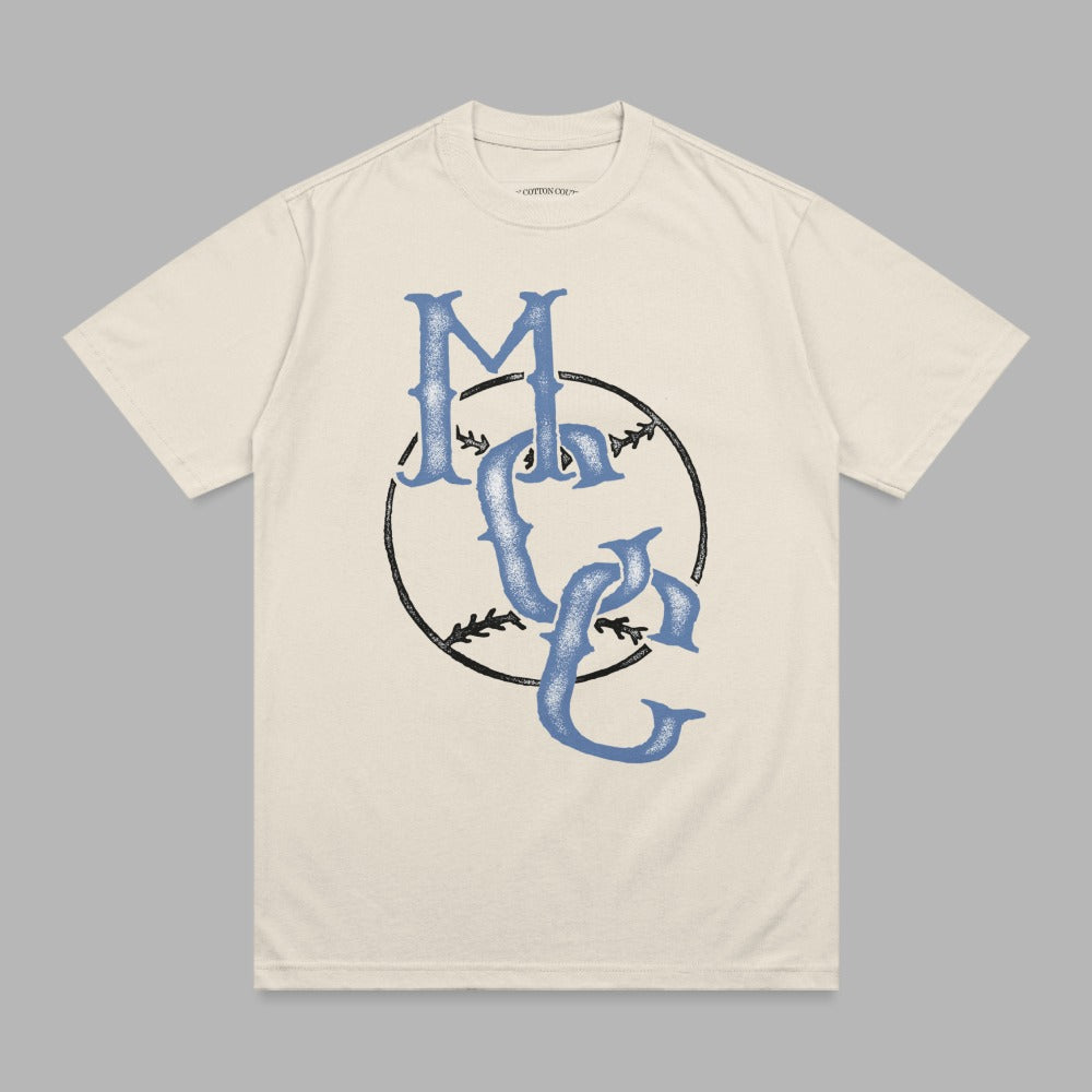 Cream t-shirt with blue "MC" logo in a baseball graphic.