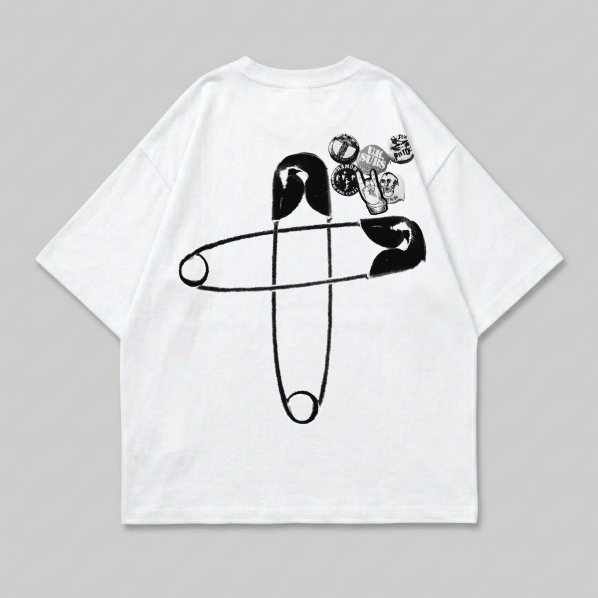 White t-shirt with large safety pin graphic and assorted band pins.