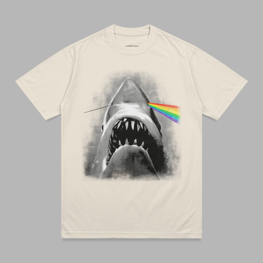 Cream t-shirt with a black and white shark biting a rainbow prism.