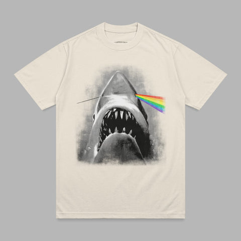 Cream t-shirt with a black and white shark biting a rainbow prism.