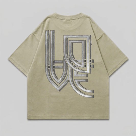 Oversized tan t-shirt with a large, metallic geometric graphic on the back.