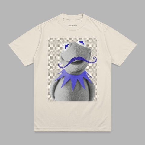 Kermit the Frog with a purple mustache and blue eyes on a cream t-shirt.