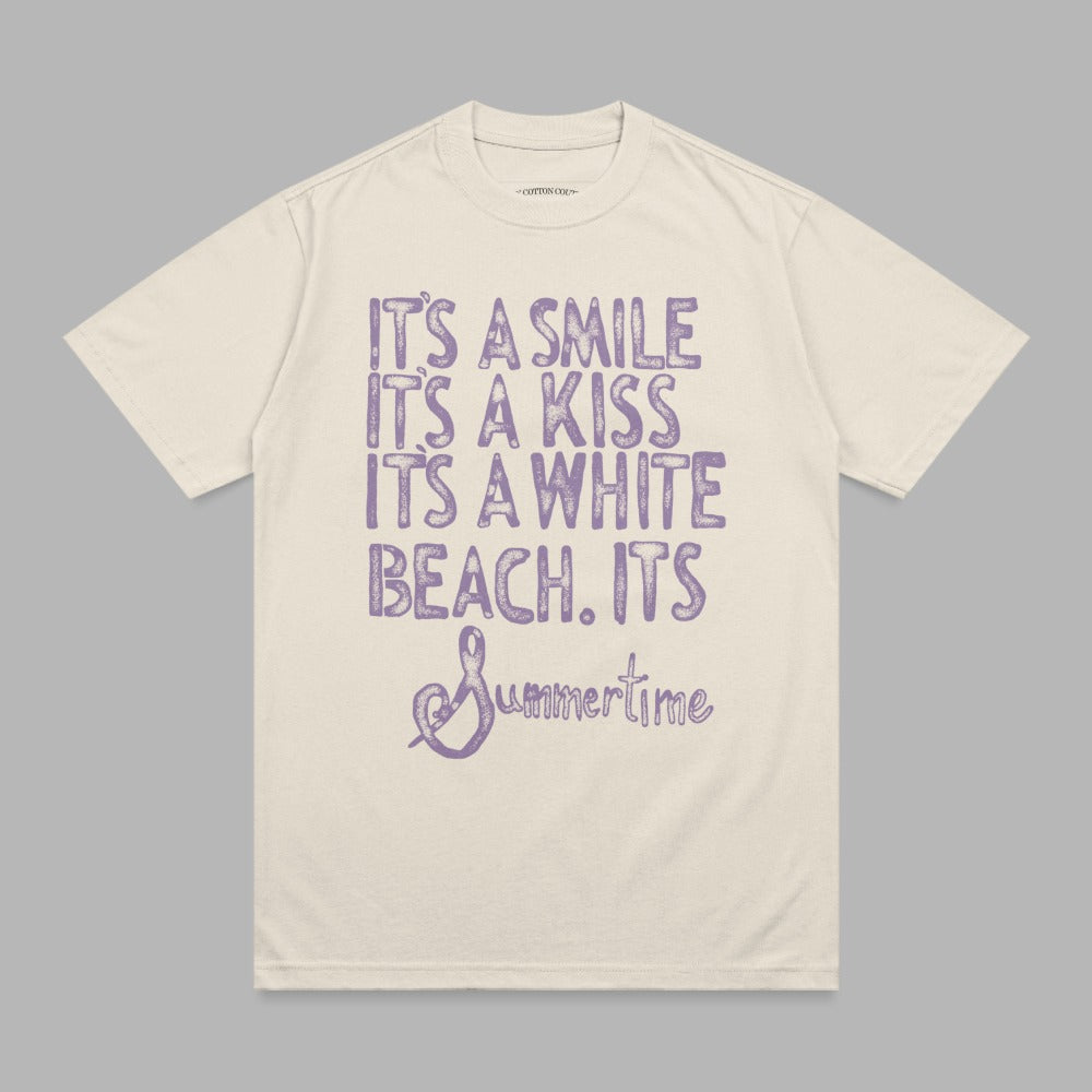 Cream t-shirt with purple distressed text "It's a smile, it's a kiss, it's a white beach, it's Summertime."