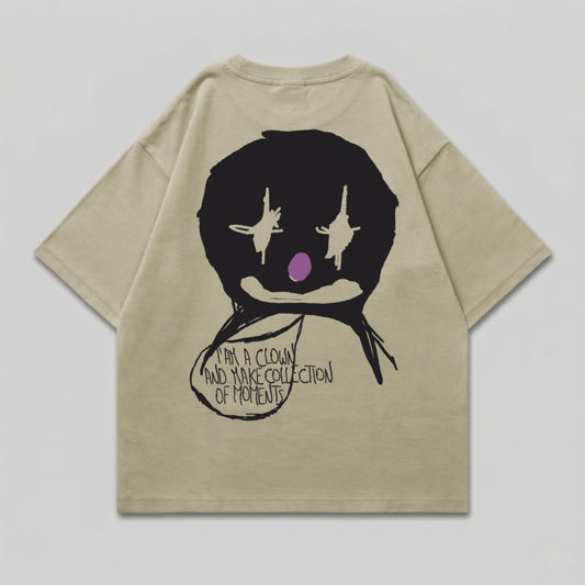 Tan t-shirt with black clown face graphic and text.
