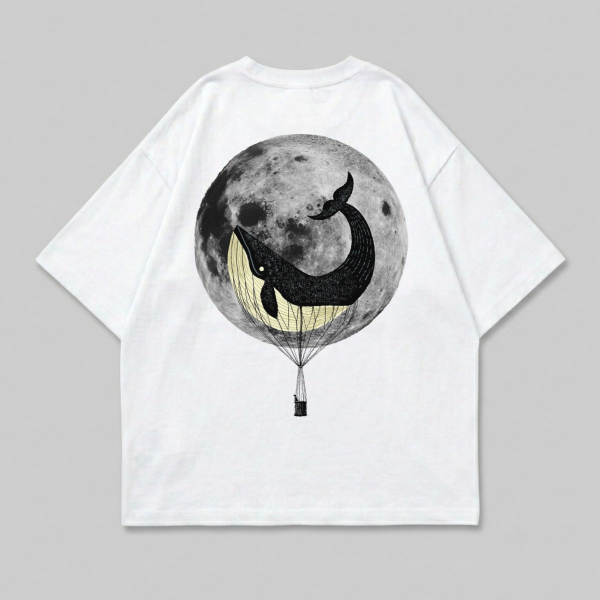 Whale in hot air balloon against full moon graphic on white t-shirt.