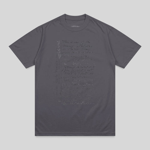 Charcoal t-shirt with handwritten text in a muted tone.