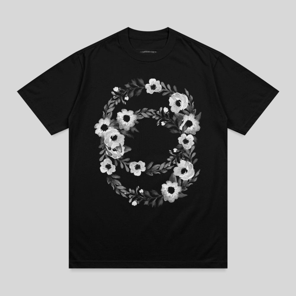 Black t-shirt with a circular floral design in shades of grey.