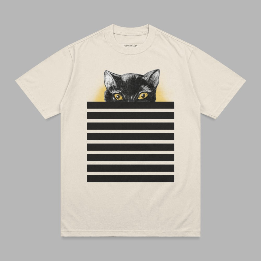 Black cat peeking over horizontal black and white stripes on a cream t-shirt.