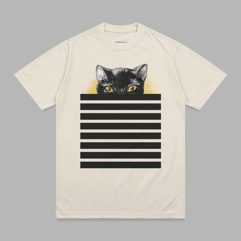 Black cat peeking over horizontal black and white stripes on a cream t-shirt.