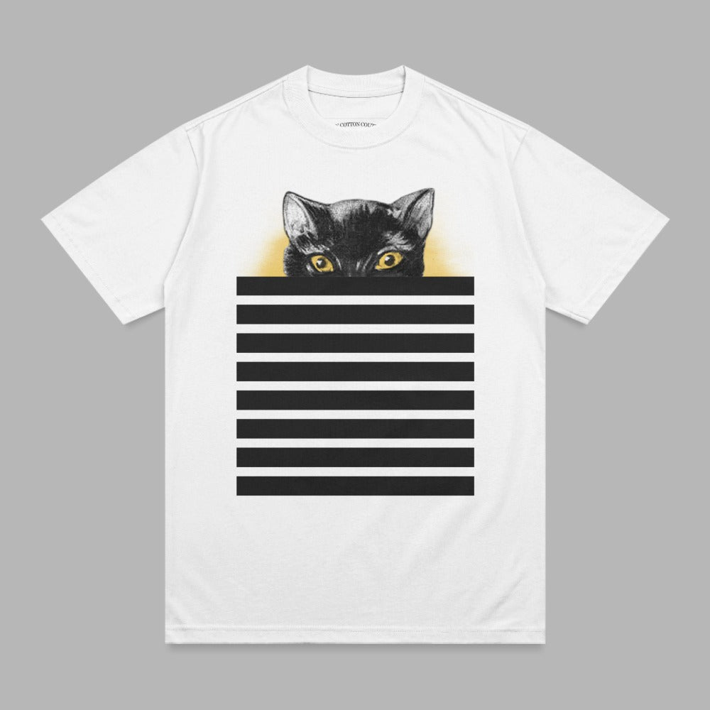 Black cat with yellow eyes peeking over black and white stripes on white t-shirt.