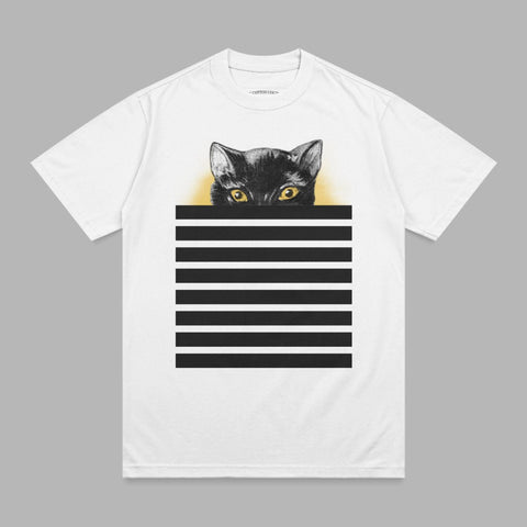 Black cat with yellow eyes peeking over black and white stripes on white t-shirt.