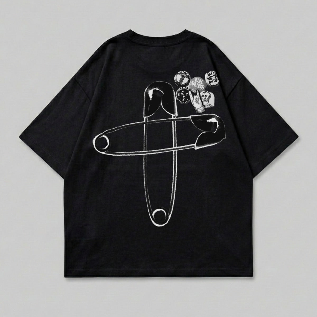 Black t-shirt with large safety pin and patches graphic on the back.