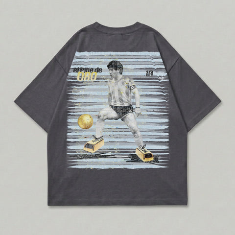 T-shirt with graphic of Diego Maradona kicking a soccer ball and "El Pibe de Oro" text.