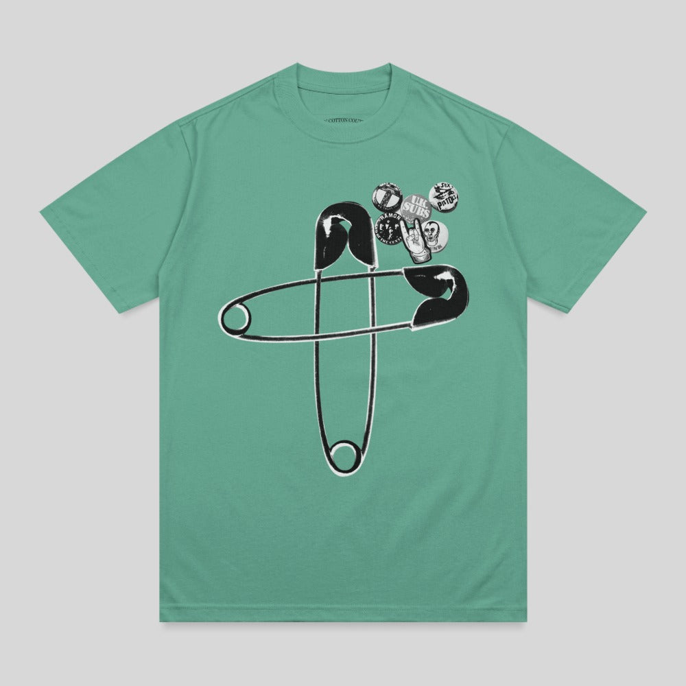 Green t-shirt with oversized safety pin and punk band pins.