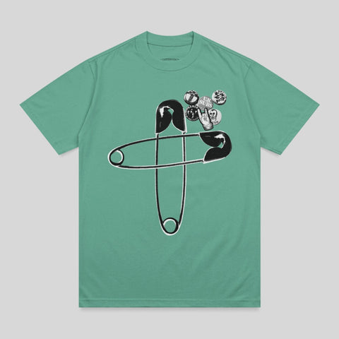 Green t-shirt with oversized safety pin and punk band pins.