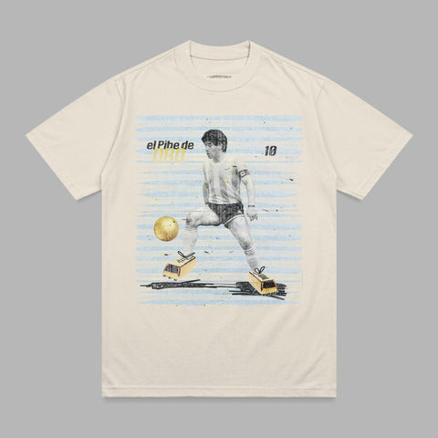 Cream t-shirt with Maradona kicking a soccer ball, "El Pihe de DAD" text.