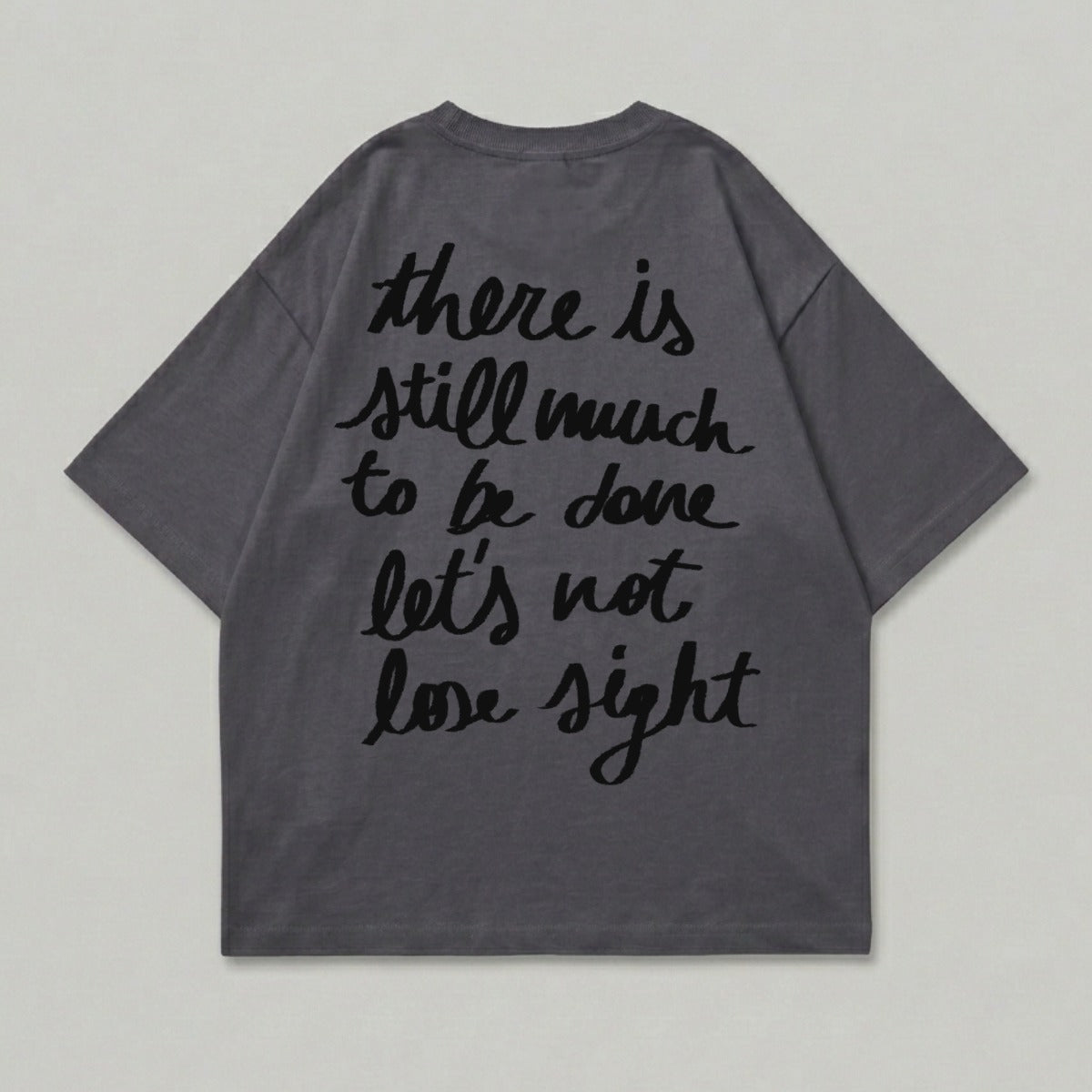 Dark grey t-shirt with black text: "there is still much to be done let's not lose sight".