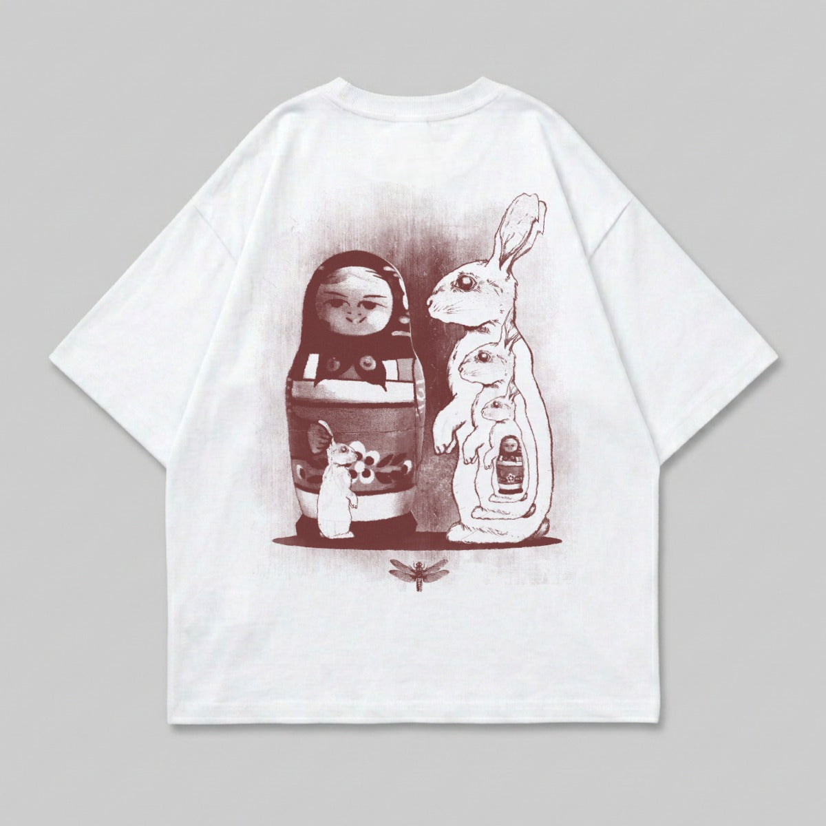 White t-shirt with matryoshka doll, rabbits, and dragonfly graphic.