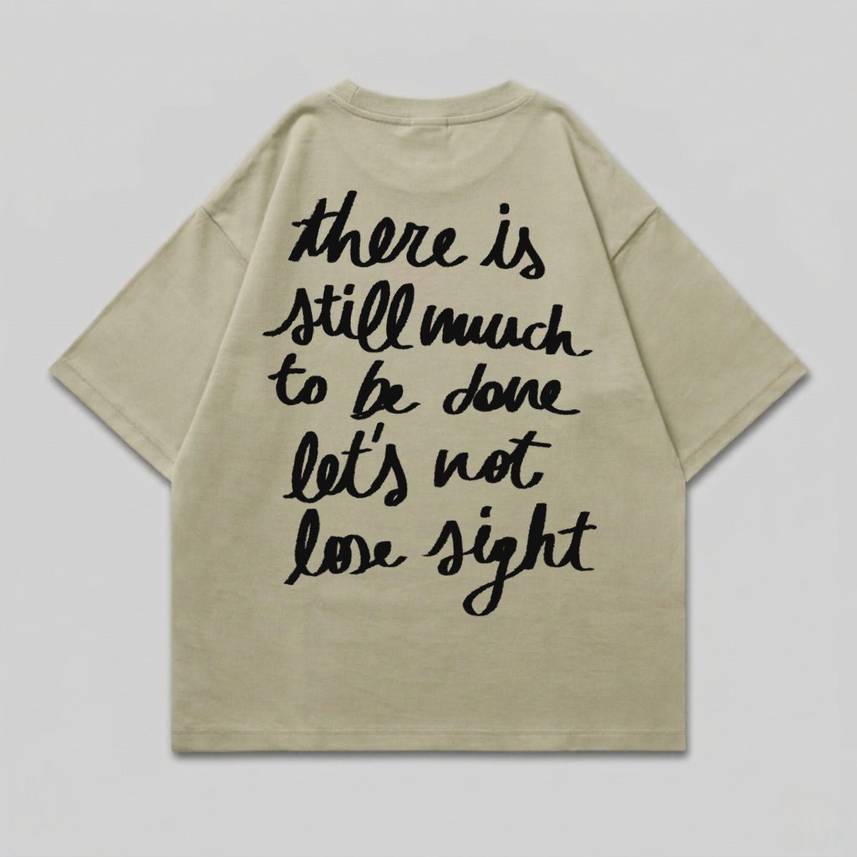 Light tan t-shirt with black script text: "there is still much to be done let's not lose sight".