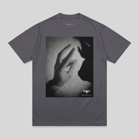 Shadow puppet of a rabbit on a t-shirt with a small dragonfly logo.