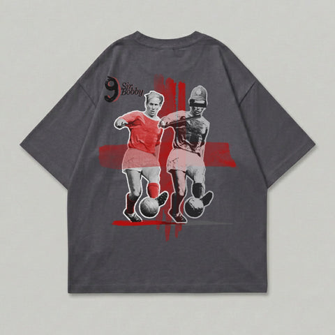 T-shirt graphic of Sir Bobby Charlton in red kit, dribbling a soccer ball.