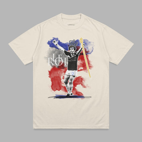 T-shirt graphic of a crowned man in celebratory pose with watercolor red, white, and blue accents.