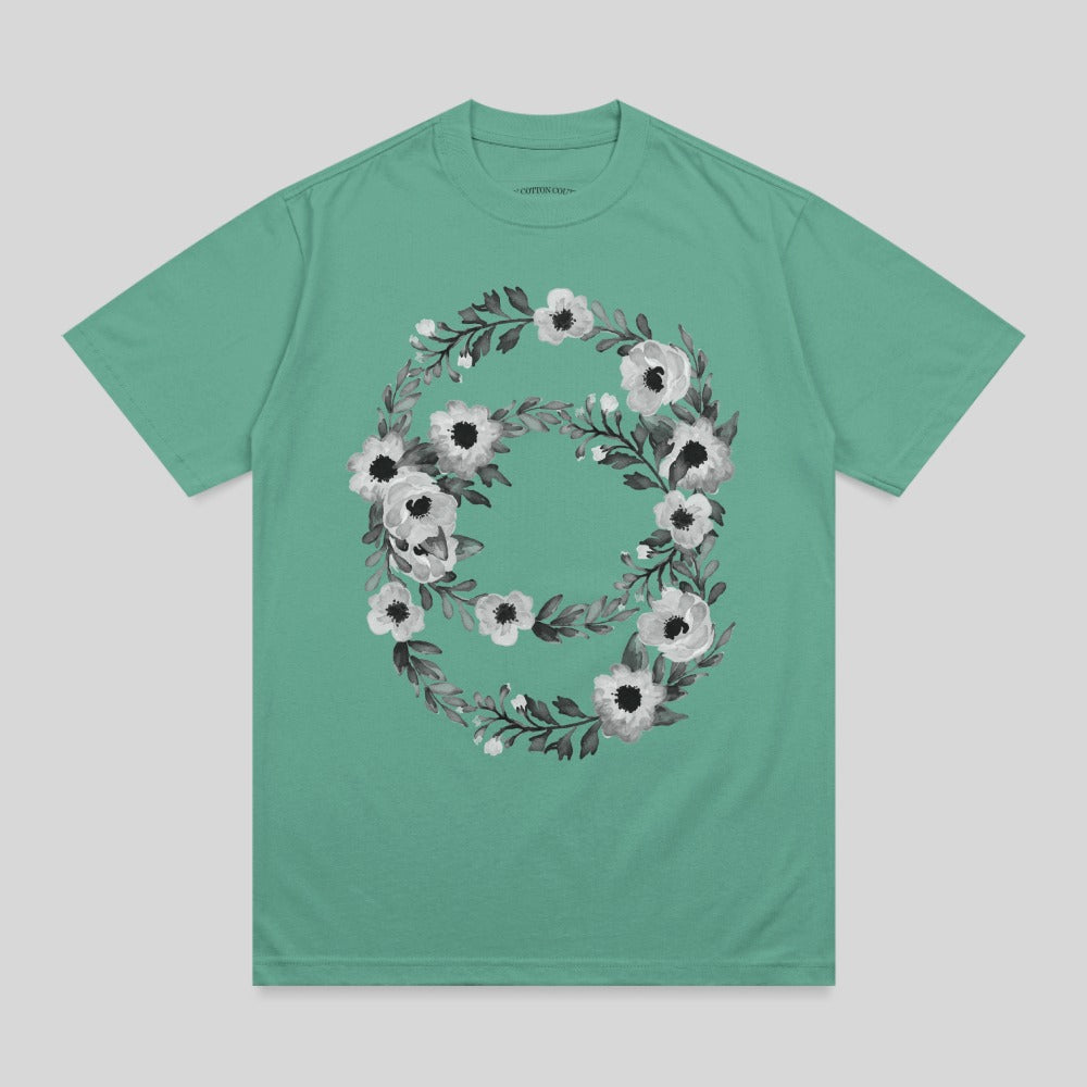 Green t-shirt with a white and black floral wreath design.