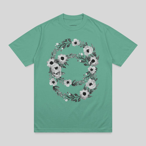 Green t-shirt with a white and black floral wreath design.