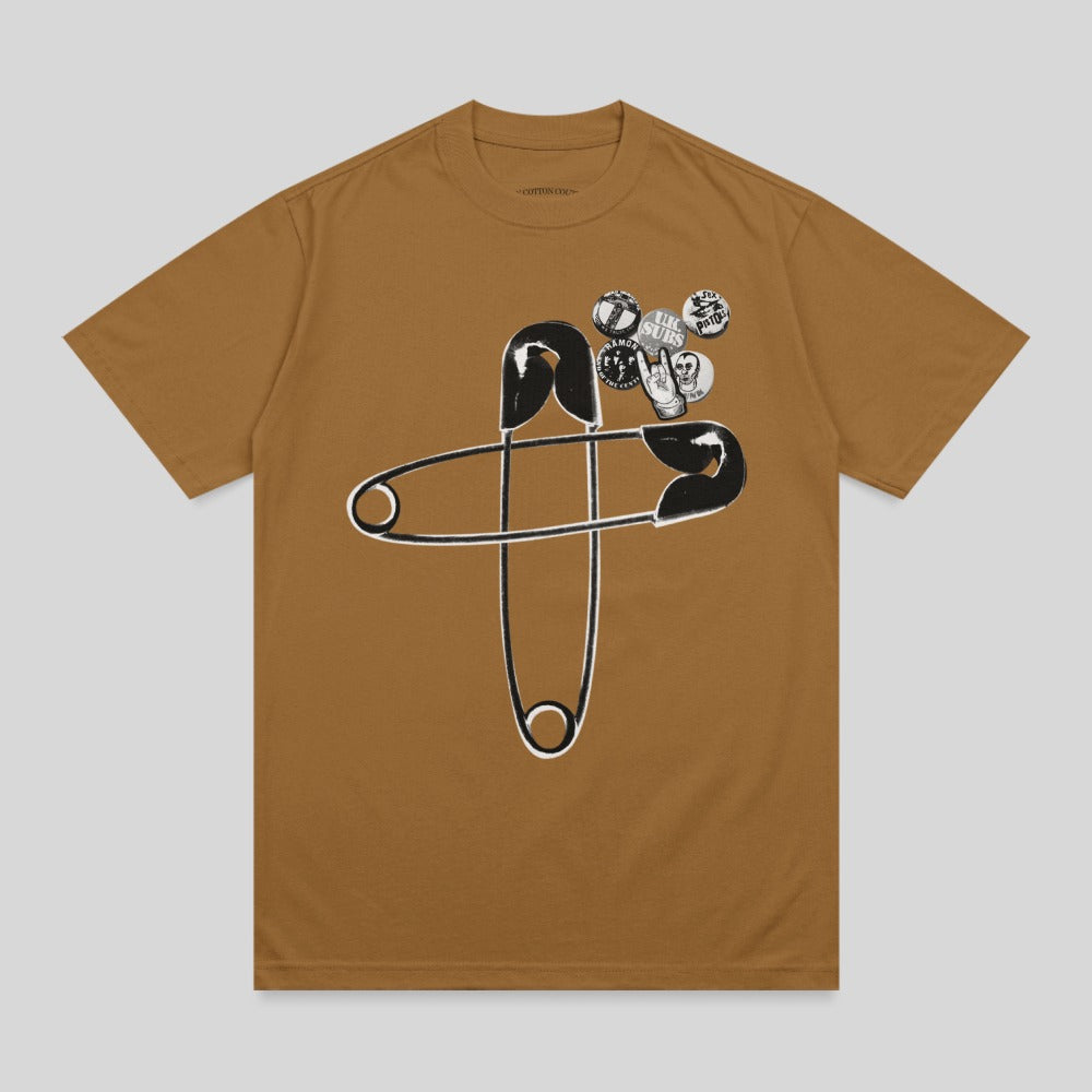 Brown t-shirt with a large safety pin and punk rock-style pins.