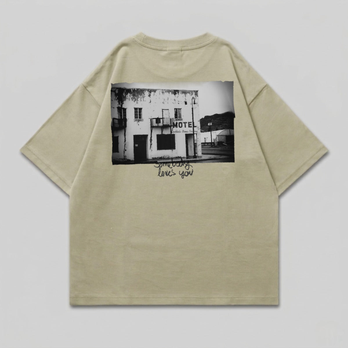 T-shirt with black and white graphic of a weathered motel and "Someone loves you" text.
