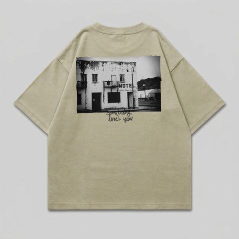 T-shirt with black and white graphic of a weathered motel and "Someone loves you" text.