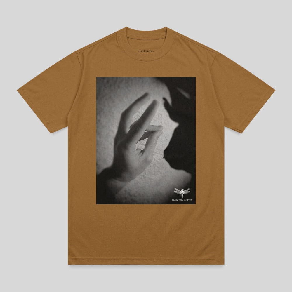 Brown t-shirt with a black and white graphic of a hand casting a shadow.
