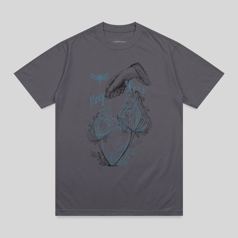 Dark grey t-shirt with illustration of hand, dragonflies, and glowing flowers.