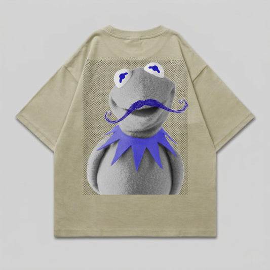 Kermit the Frog wearing a blue mustache and purple collar on a tan t-shirt.